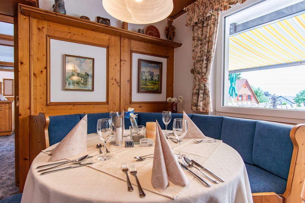 Klassischer Restaurantbereich mit elegant eingedecktem Tisch und gemütlicher runder Sitzbank im Wellnesshotel Hohenrodt