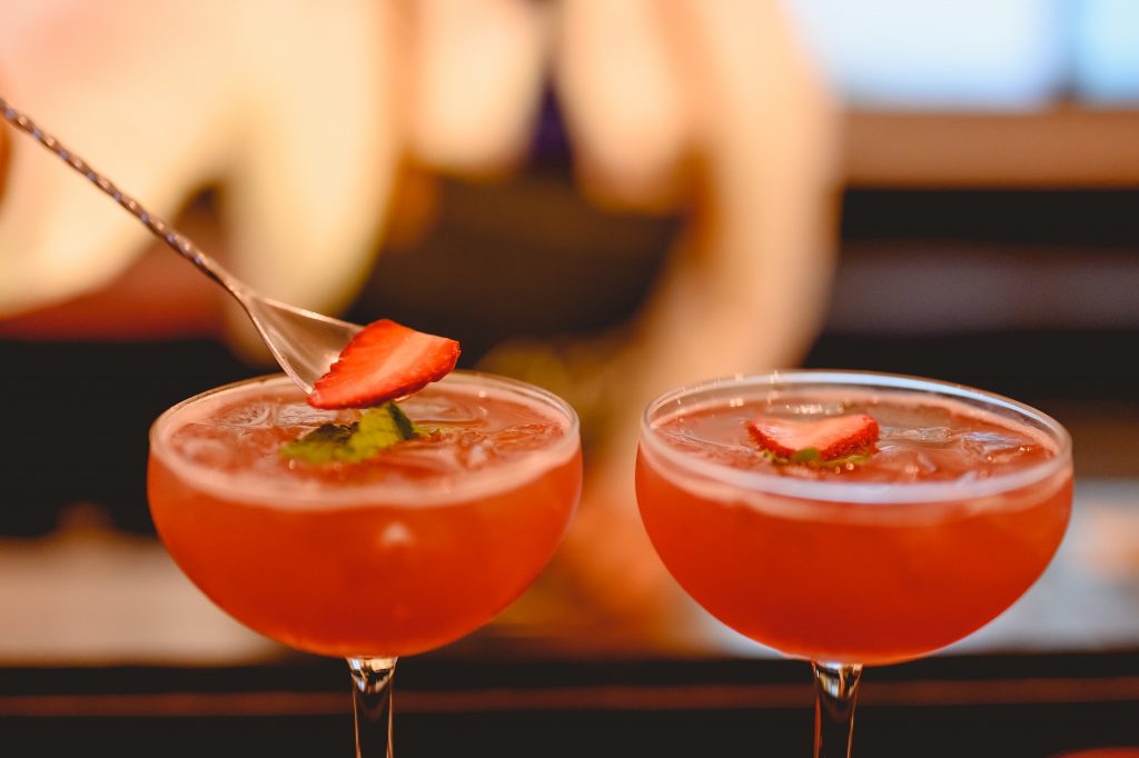 Barkeeper bereitet einen Cocktail zu und dekoriert ihn in einem Martini-Glas für eine ansprechende Präsentation an der Bar eines Wellnesshotels