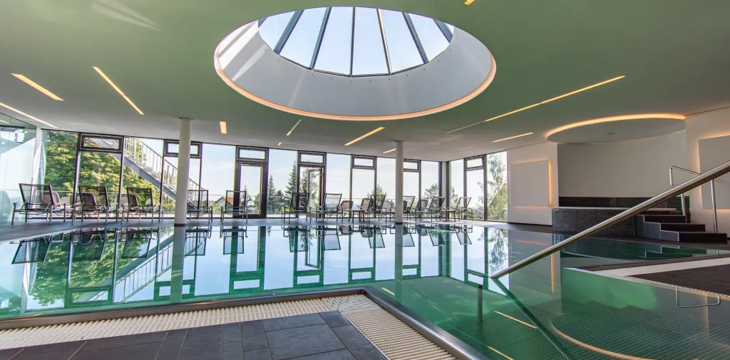 Wellnesshotel Hohenrodt, Wellness-Poolbereich mit Hallenbad, Tageslicht und einer Glaskuppel für ein lichtdurchflutetes und entspannendes Ambiente